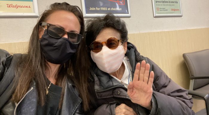Two women, wearing masks, wait for a vaccine appointment