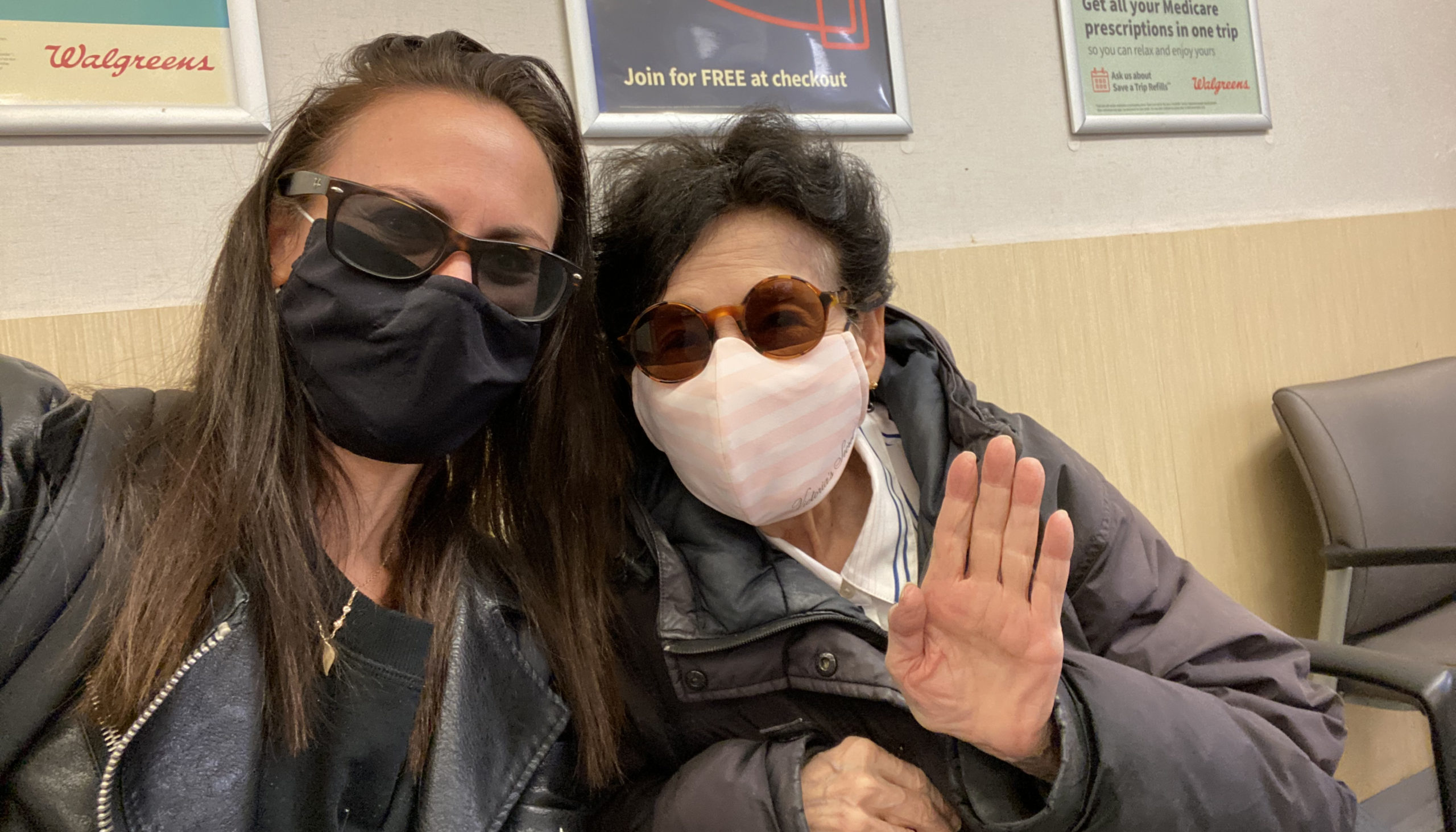 Two women, wearing masks, wait for a vaccine appointment